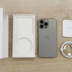 Flat lay view of the newest Apple iPhone model, box, and charging accessories on a wooden table.
