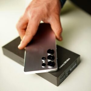 Close-up of hand holding Samsung Galaxy S25 Ultra smartphone with box.